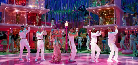 Barbie (Margot Robbie) and five Kens clap their hands above their head in a choreographed dance scene.