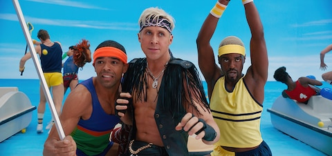 Ken (Ryan Gosling), dressed in a leather fringe vest, is flanked by two other Kens in activewear as they prepare to fight.