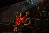Behind the scenes, Blitz Bazawule directs Fantasia Barrino and Taraji P. Henson who are seated in a theater wearing beaded evening dresses.