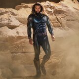 Aquaman walks through a rock formation in his stealth suit.