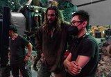 Behind the scenes, Jason Momoa and director James Wan look at a monitor on set.