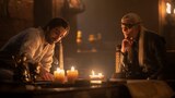 Ser Criston Cole and Prince Aemond Targaryen sit around a low table, looking at documents.