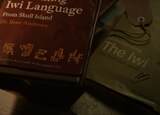 ASL performer Otis Jones signs “ancestral” in front of a scene from the movie that shows two books about the Iwi from Skull Island written by Dr. Ilene Andrews.
