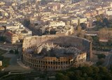 ASL performer Otis Jones signs “alarm sound” in front of a scene from the movie that shows Godzilla resting inside the Roman Colosseum, his body spread out the length of the amphitheater.