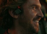 ASL performer Otis Jones signs “woo-hoo” in front of a scene from the movie that shows Trapper smiling while wearing a headset.