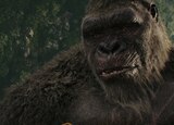 ASL performer Otis Jones signs “rip it out” in front of a scene from the movie that shows Kong calmly looking down at something out of frame.