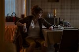 Francis Cobb sits at a cluttered kitchen table and looks at something out of frame.