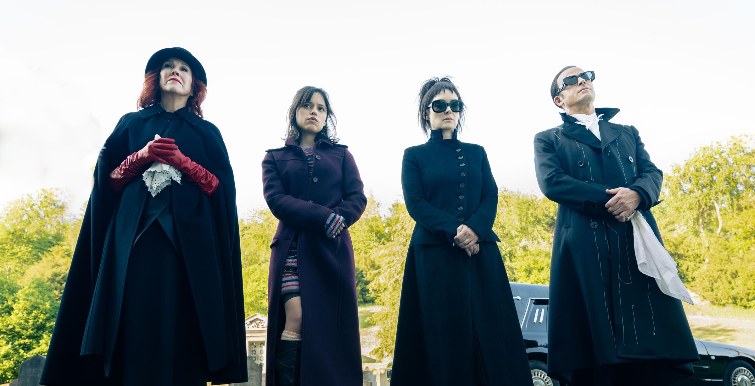 Delia Deetz, Astrid Deetz, Lydia Deetz, and Rory are dressed in funeral attire and stand solemnly in a cemetery.