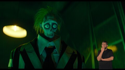 Bob (Shrinker) olha fixamente para algo fora de quadro. O intérprete de Libras, Andrey Baptista, está no canto inferior direito e sinaliza "mudo".