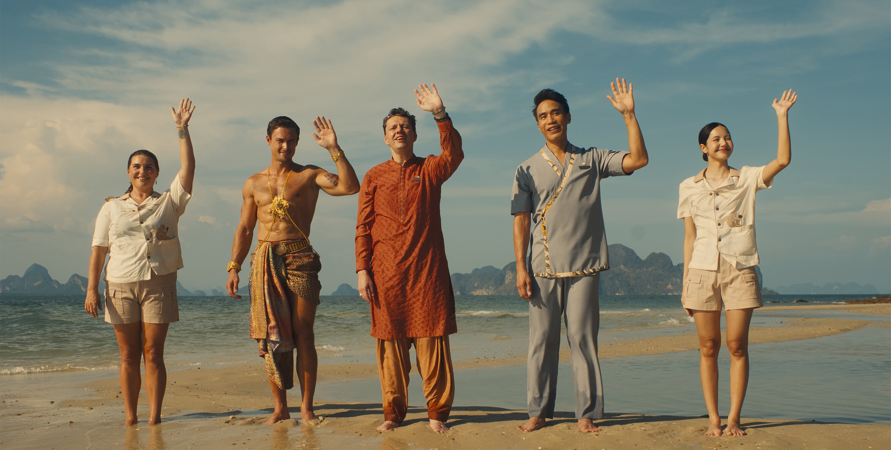 Five employees of The White Lotus stand on the shore and wave. 