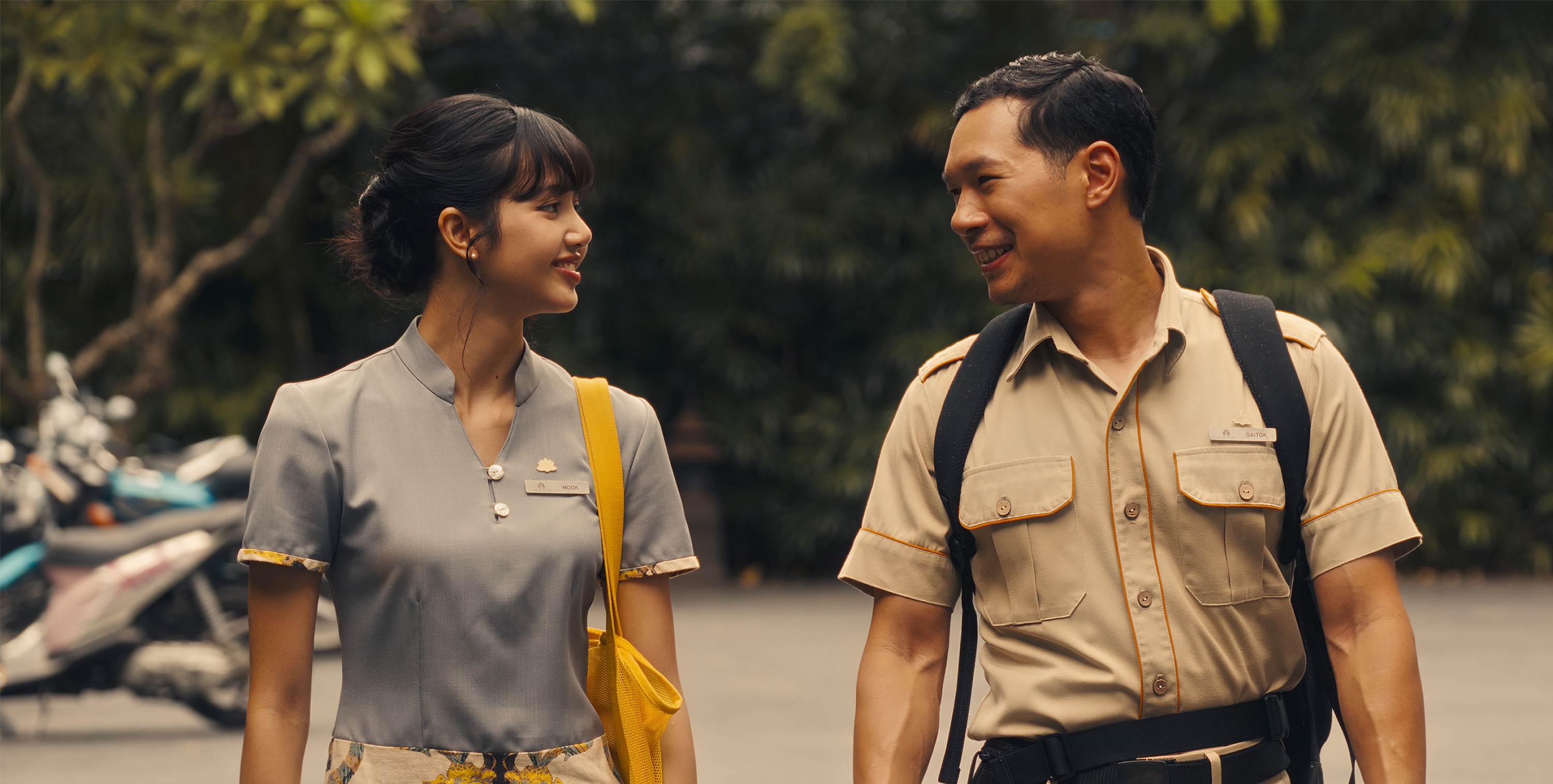 Mook (Lalisa Manobal) and Gaitok (Tayme Thapthimthong) stand side by side and smile at each other. 