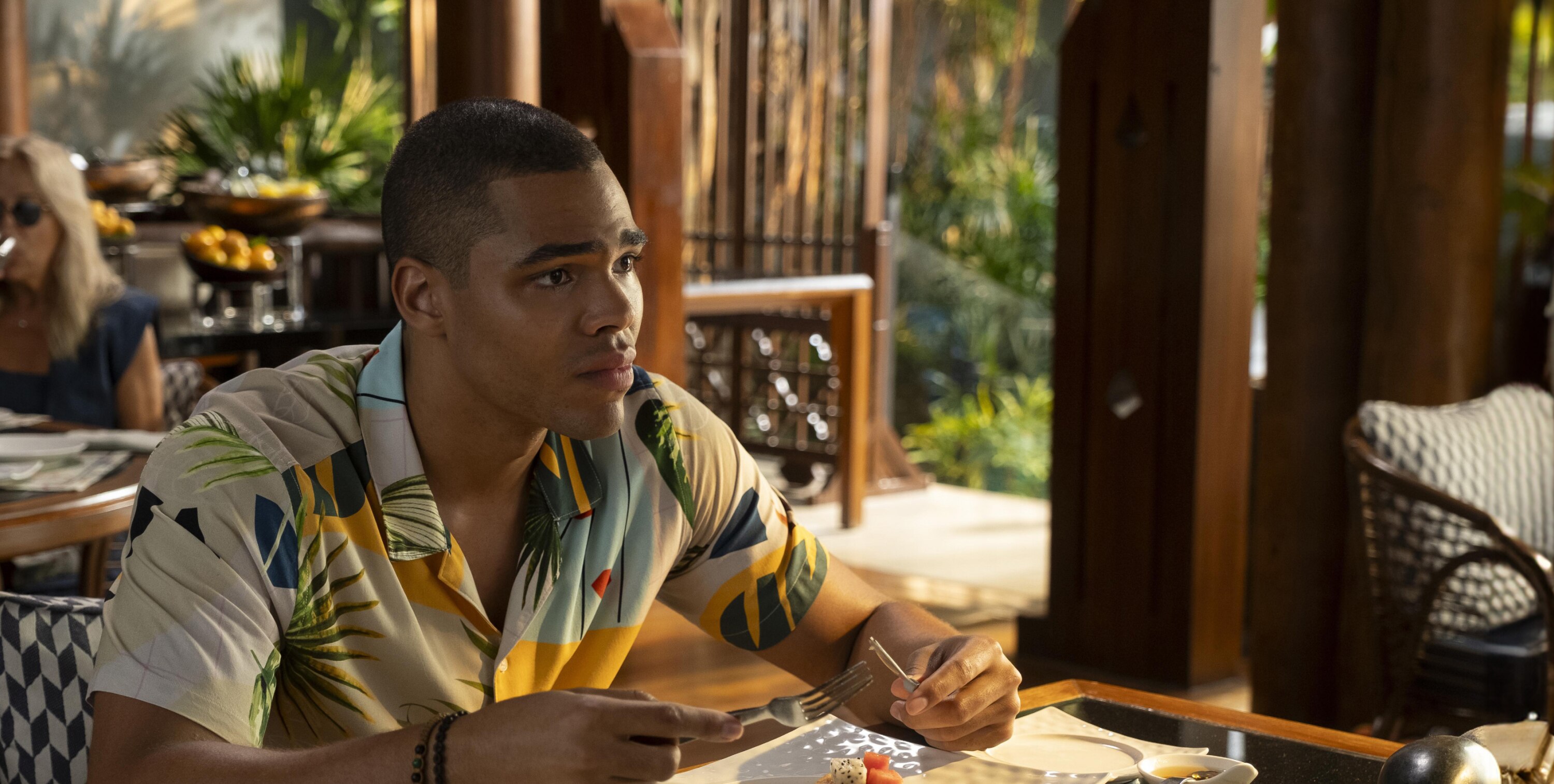 Zion (Nicholas Duvernay) is seated at a table, having breakfast and engaged in conversation. 