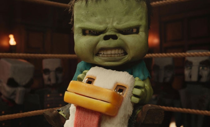 The chicken jockey, a baby zombie riding a chicken, stands in a fighting ring with a ferocious expression on its face. Four bald, gray-skinned people in military-style uniforms stand outside the ring behind the chicken jockey. ASL interpreter Sophia Morales signs “screaming.”