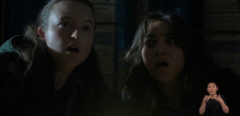Ellie and Dina look at something out of frame with shocked expressions. ASL interpreter Leila Hanaumi signs “sounds.”