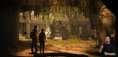 Joel and Ellie stand in an abandoned museum. Ellie looks ahead at a space capsule and space suits on display while Joel looks at her. ASL interpreter Daniel Durant signs “where.”