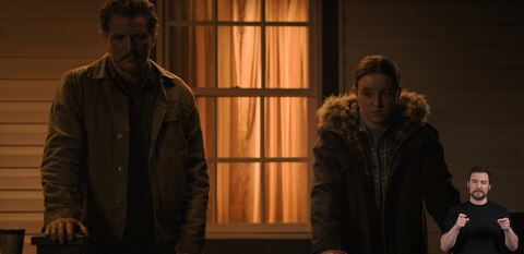 Joel and Ellie stand on the front porch of their house and rest their hands on the railing. They look in different directions. ASL interpreter Daniel Durant signs “control.”