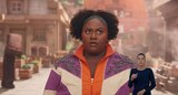 Dawn, wearing a purple, orange, and white jacket with bejeweled shoulders, looks at something out of frame. ASL interpreter Sophia Morales signs “uh-oh.”