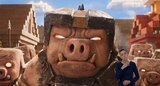 Close-up of General Chungus, a large piglin wearing a bulky collar and a helmet with a gold streak and black spikes. At least six smaller piglins stand behind him. ASL interpreter Sophia Morales signs “curious.”