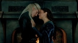 Alicent Hightower and Aemond Targaryen stand close together in front of a large fireplace, touching foreheads. Alicent’s eyes are closed as she touches Aemond’s chest with her left hand. Aemond’s arms are at his sides, and he is looking down.