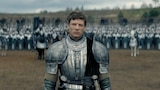 Ormund Hightower stands in the foreground of an open field wearing polished metal armor. In the blurred background, a large formation of soldiers with shields, lances, and banners stands at the ready.