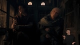 Larys Strong and King Aegon II sit inside a dimly lit wooden cage. Larys holds a cane and looks to his right. Aegon leans against the wall of the cage with his eyes closed, seemingly asleep. In the bottom right side of the image, ASL dubber Landen Gonzales signs "Another."