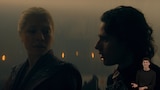 Rhaenyra Targaryen and her son Jacaerys Velaryon stand side by side in a dim, candlelit interior. Rhaenyra has a slightly concerned expression while Jacaerys looks straight ahead. In the bottom right side of the image, ASL dubber Landen Gonzales signs “Huh? (disappointed).”